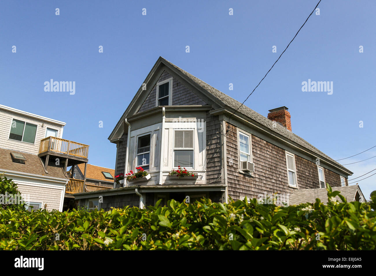 Guardando oltre una siepe verso i piani superiori di un vecchio incastrata in casa a Provincetown, Massachusetts Foto Stock