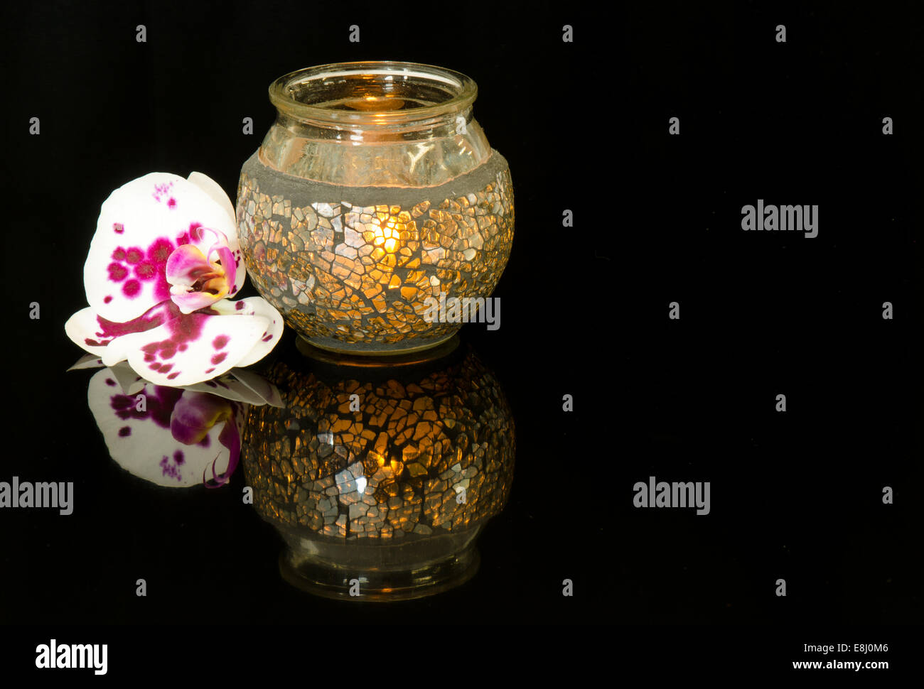 Una phalaenopsis orchid e candela su una riflessione sullo sfondo nero Foto Stock