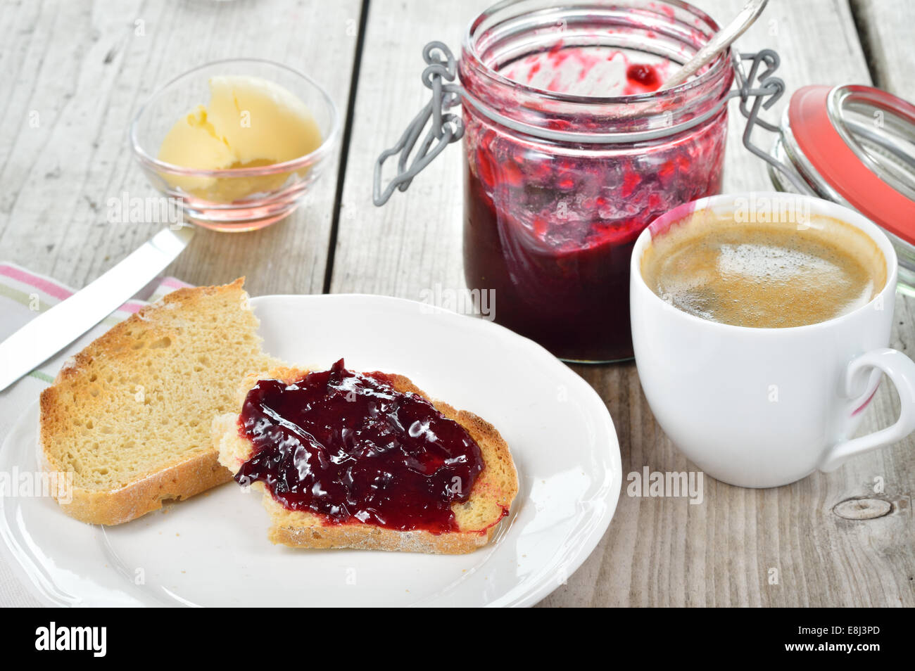 Dolce colazione con pane tostato, marmellata di prugne, il burro e il caffè sul tavolo di legno. Foto Stock
