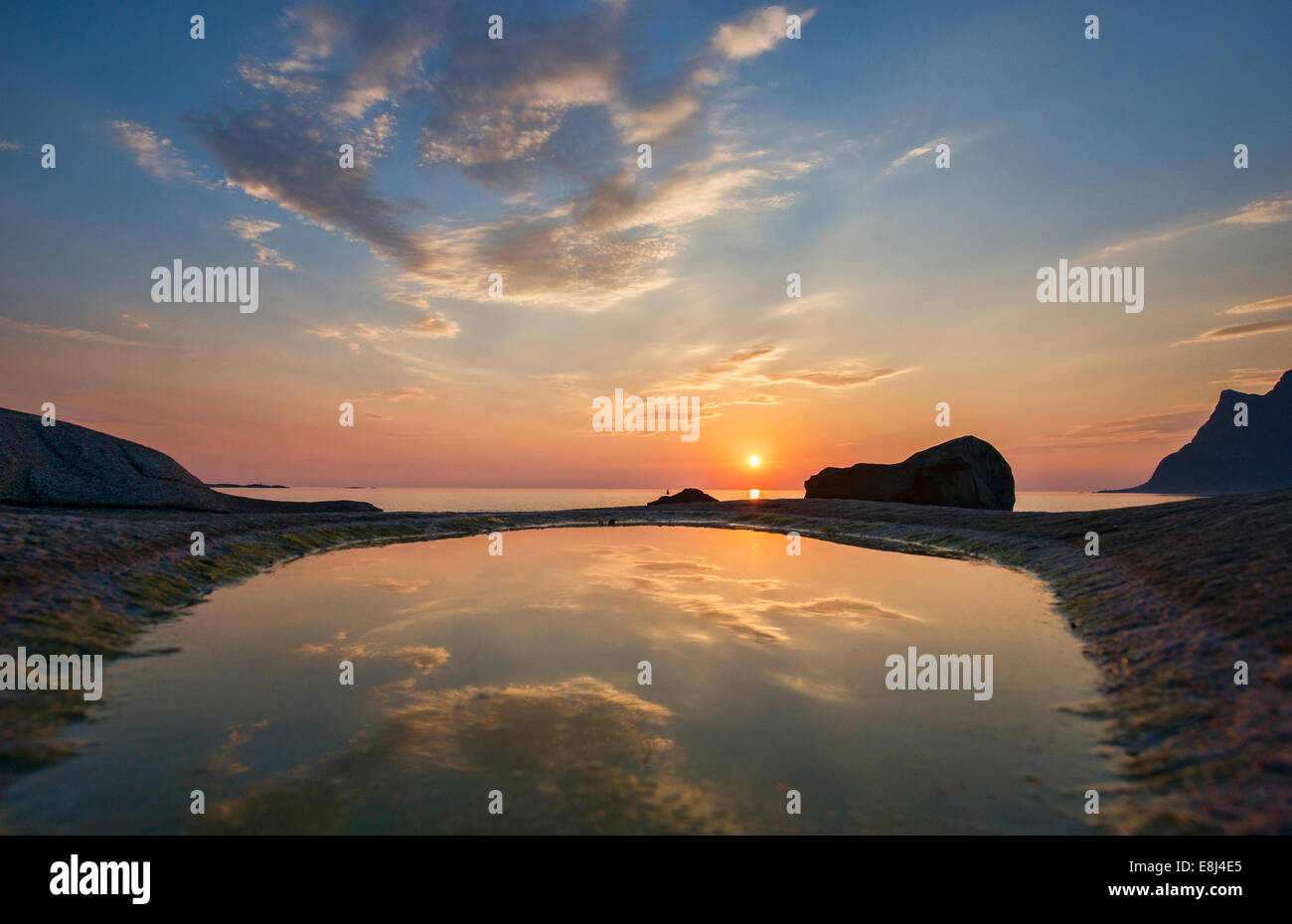 Il sole di mezzanotte oltre l'Artico dalla spiaggia Uttakleiv nelle Isole Lofoten in Norvegia Foto Stock