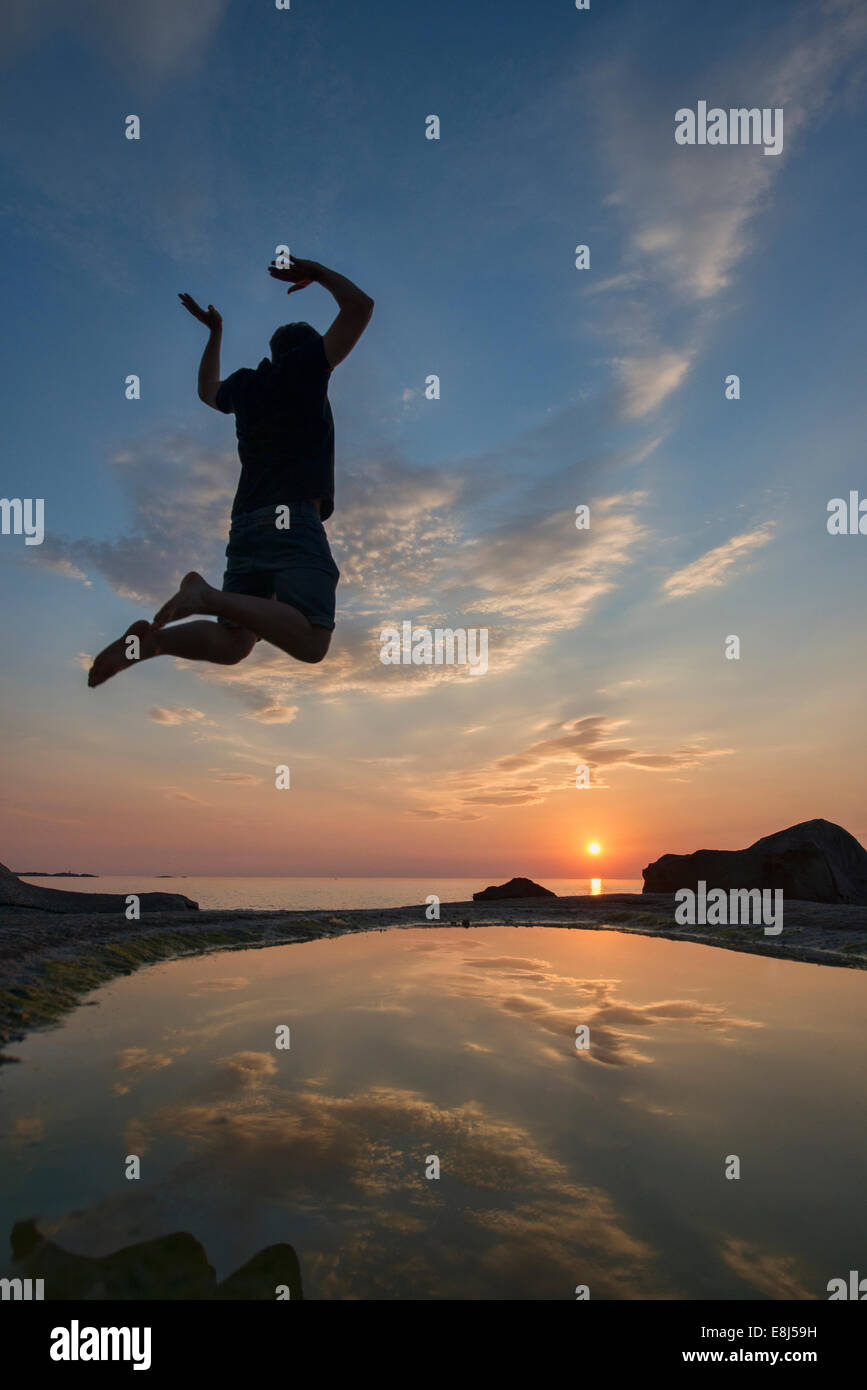 Godendo il sole di mezzanotte sulla bellissima spiaggia di Uttakleiv nelle Isole Lofoten in Norvegia Foto Stock