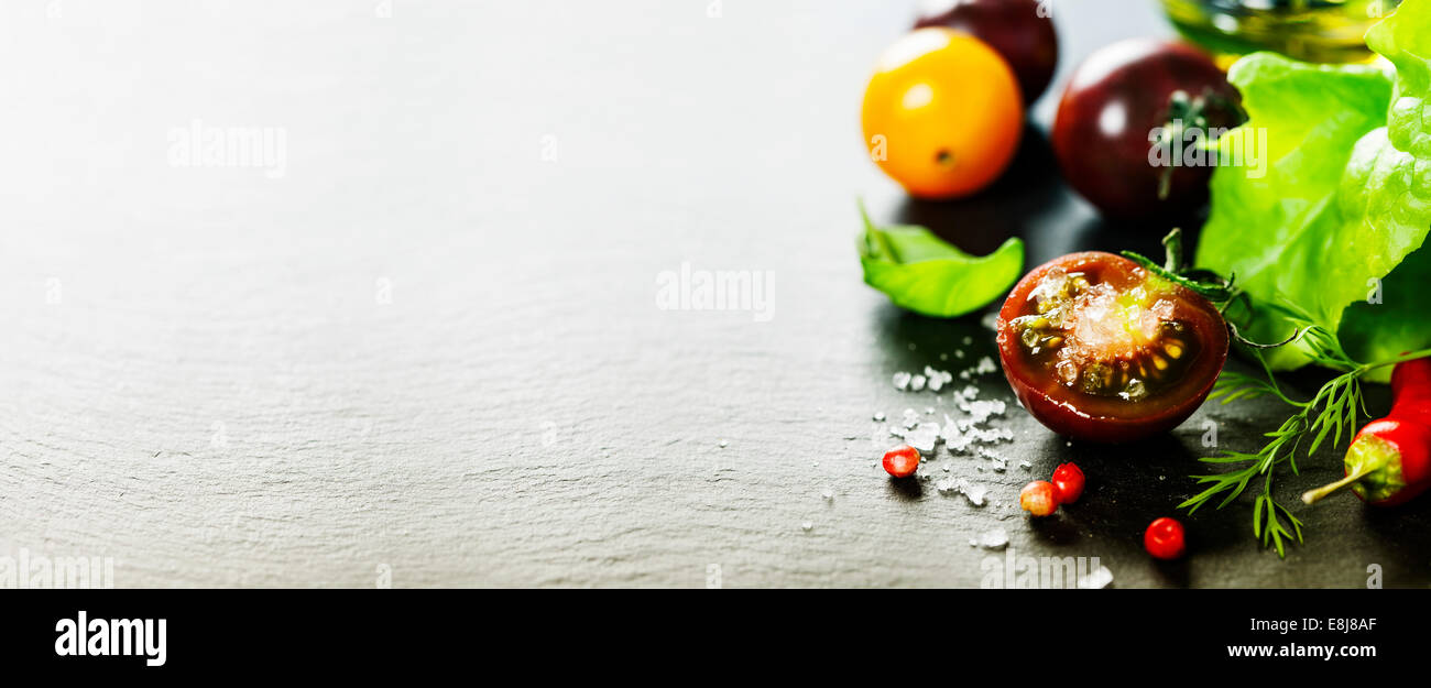 Mosti di uve fresche pomodori con foglie di insalata e sale per l'uso come ingredienti di cottura con pomodoro dimezzata in primo piano con copyspace Foto Stock