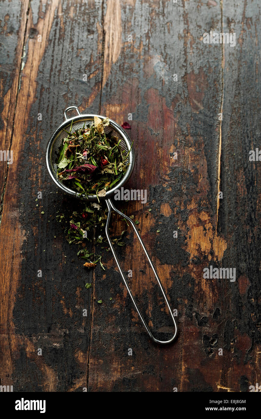 Stainer tè aromatico con tè alle erbe su un tavolo di legno sfondo Foto Stock