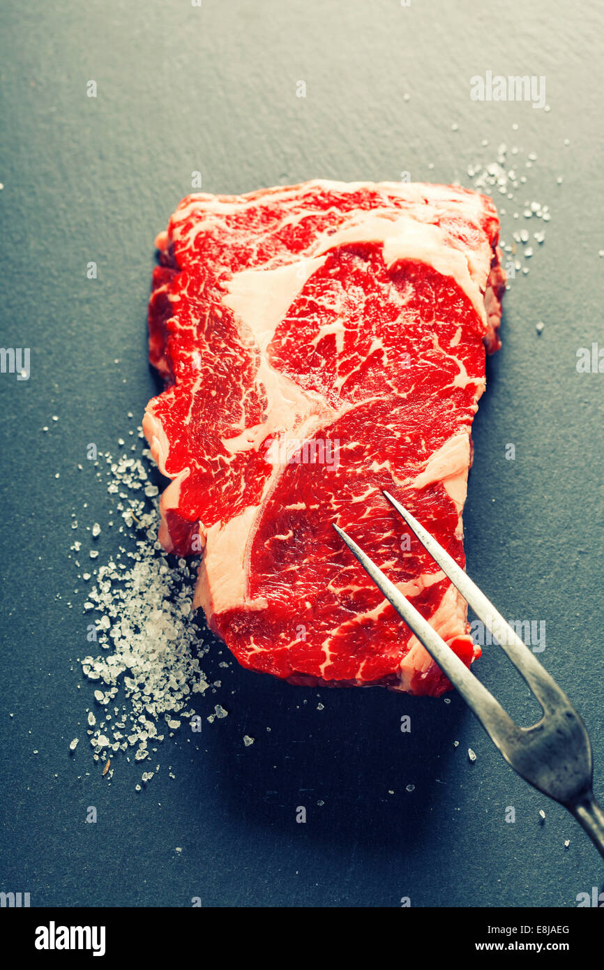 Materie bistecca di carne la forcella al buio su un sfondo di ardesia Foto Stock