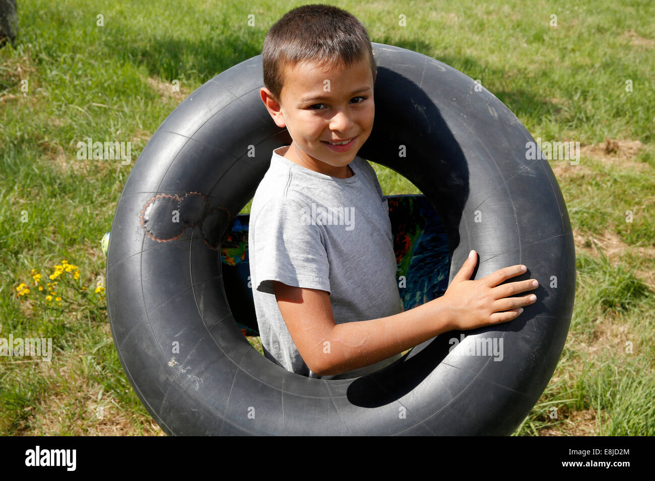 Ragazzo che porta un pneumatico usato come una boa Foto Stock