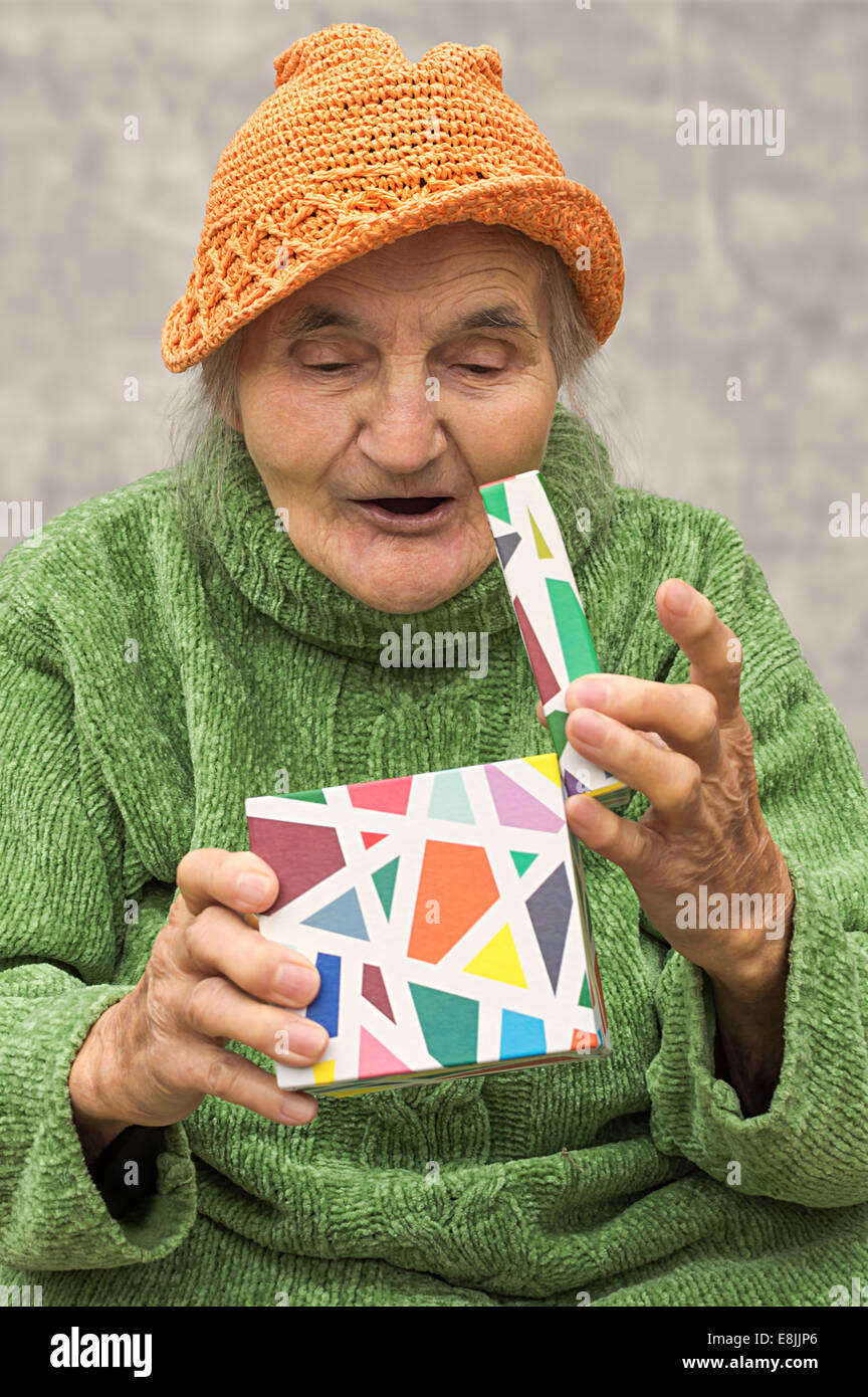 Felice e sorpreso donna anziana dopo apertura della confezione regalo. Foto Stock
