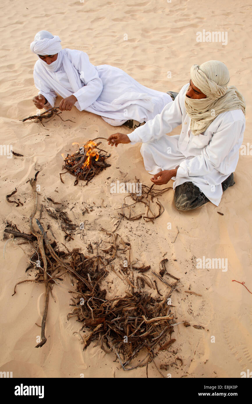 Beduins seduto da un incendio nel Sahara Foto Stock