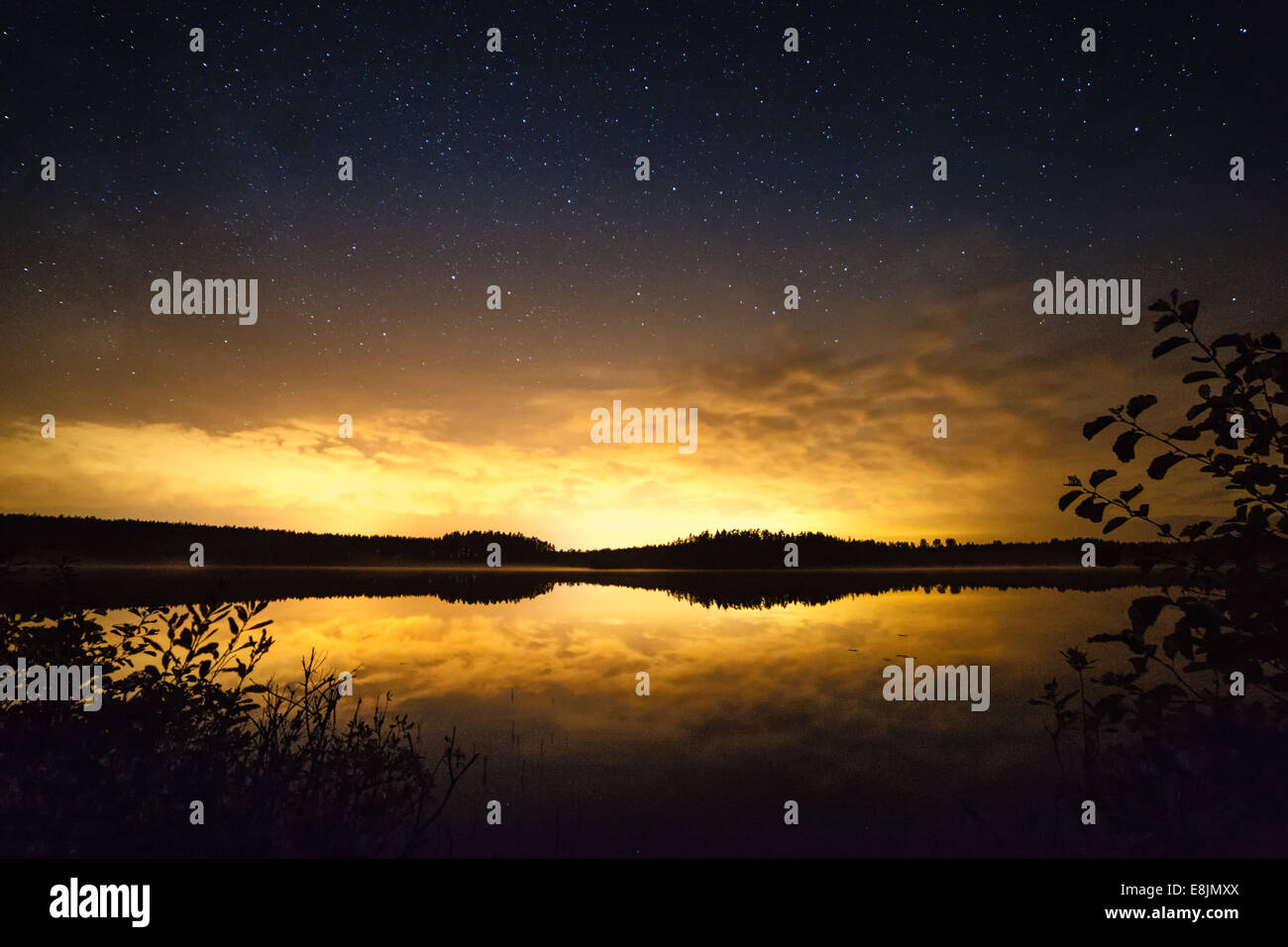 Stelle sopra la scena al tramonto in Finlandia. Le riflessioni della foresta skyline nelle calme acque di un lago. Foto Stock