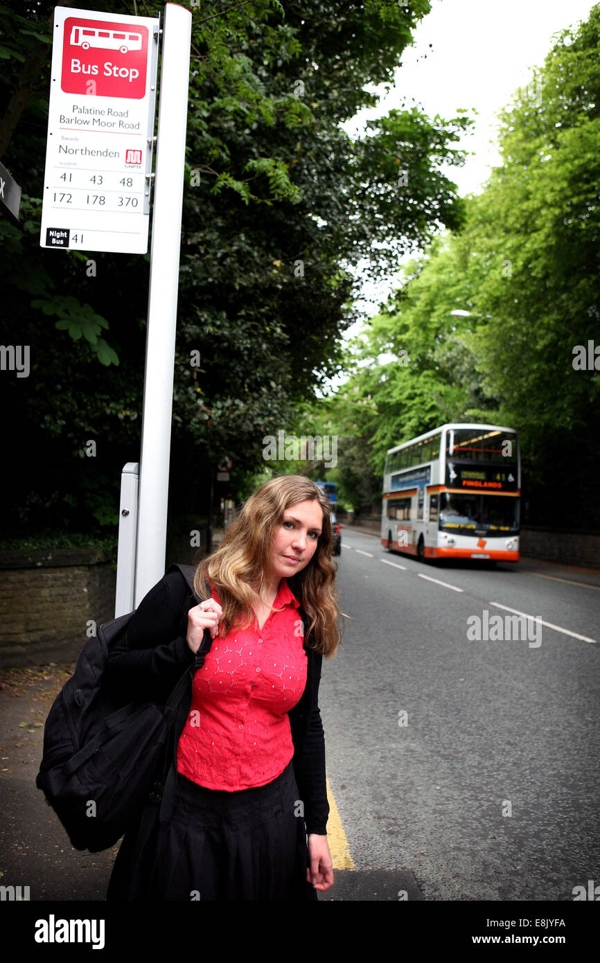 Una donna attende un bus a Manchester REGNO UNITO Foto Stock