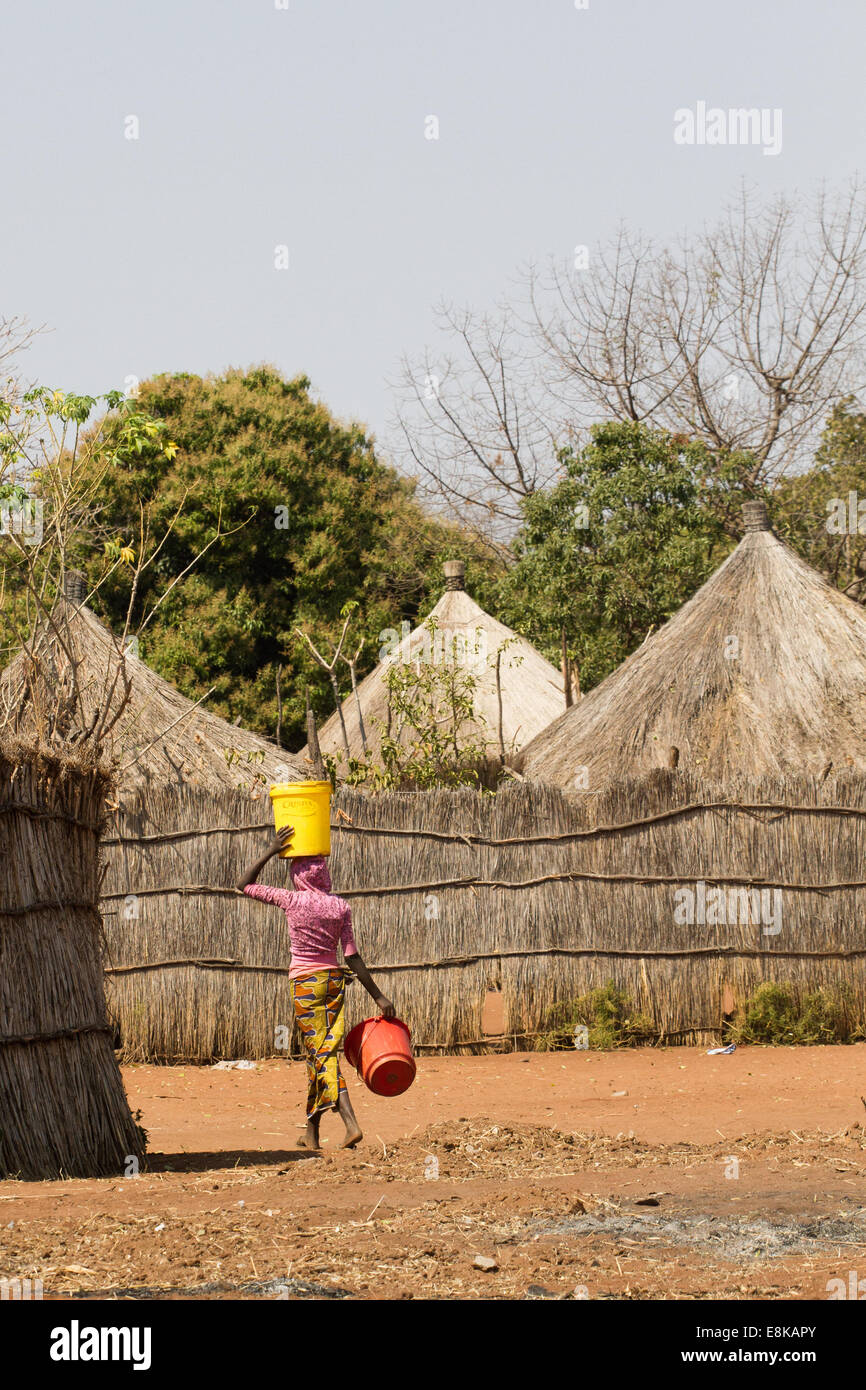 Un zambiani / donna africana in un tipico villaggio tradizionale porta acqua in un contenitore sulla sua testa Foto Stock Un zambiani / donna africana in un tipico villaggio tradizionale porta acqua in un contenitore sulla sua testa Foto Stock
