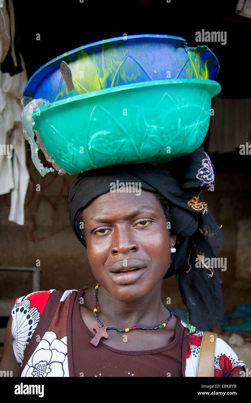 Donna con vaschette di cibo per la vendita equilibrato sul suo capo, Kroo Bay, a Freetown, in Sierra Leone. Foto © Nilo Sprague Foto Stock
