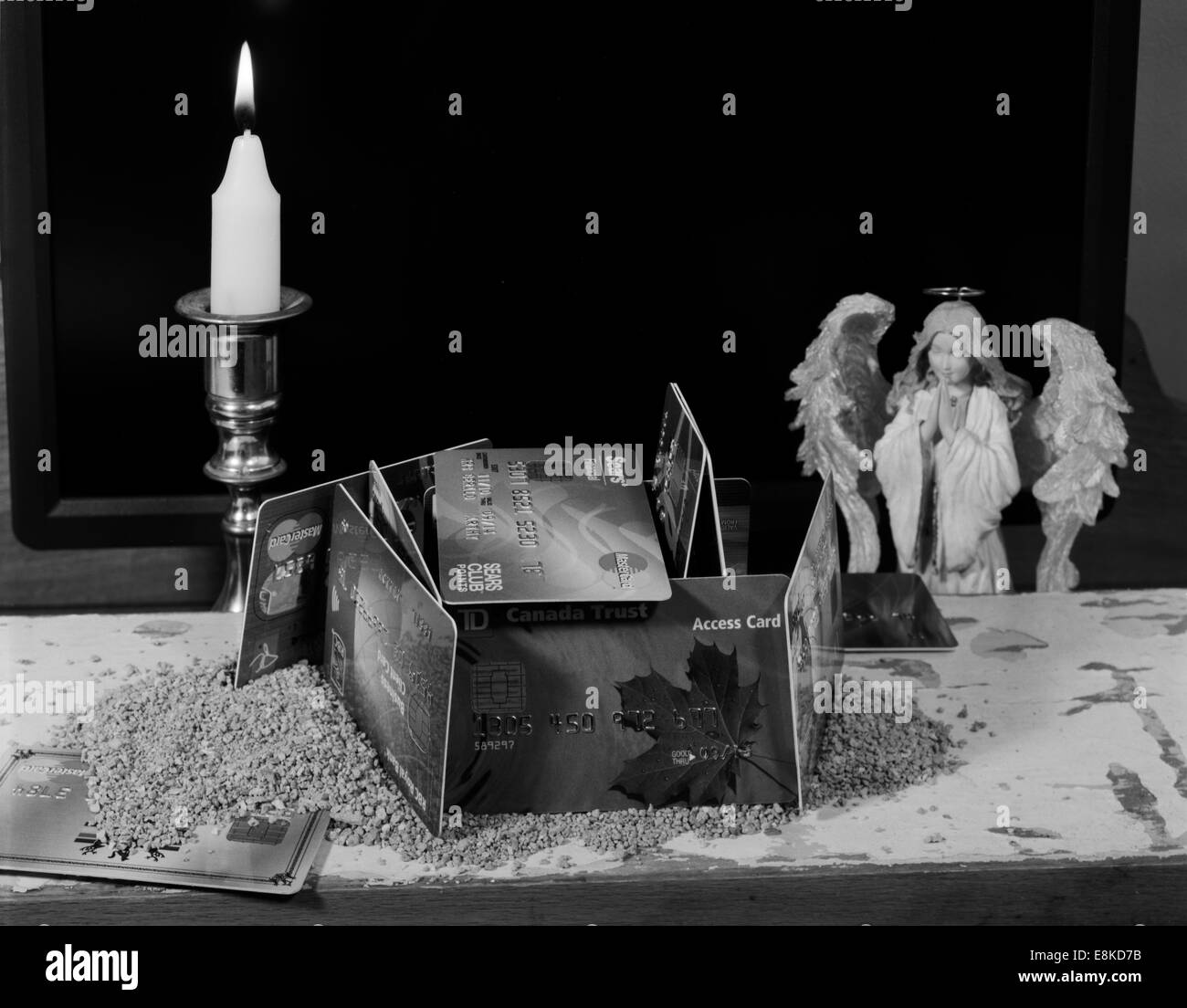 Le carte di plastica da istituzioni finanziarie costruito come una casa sulla sabbia con angelo che prega per la stabilità finanziaria Foto Stock