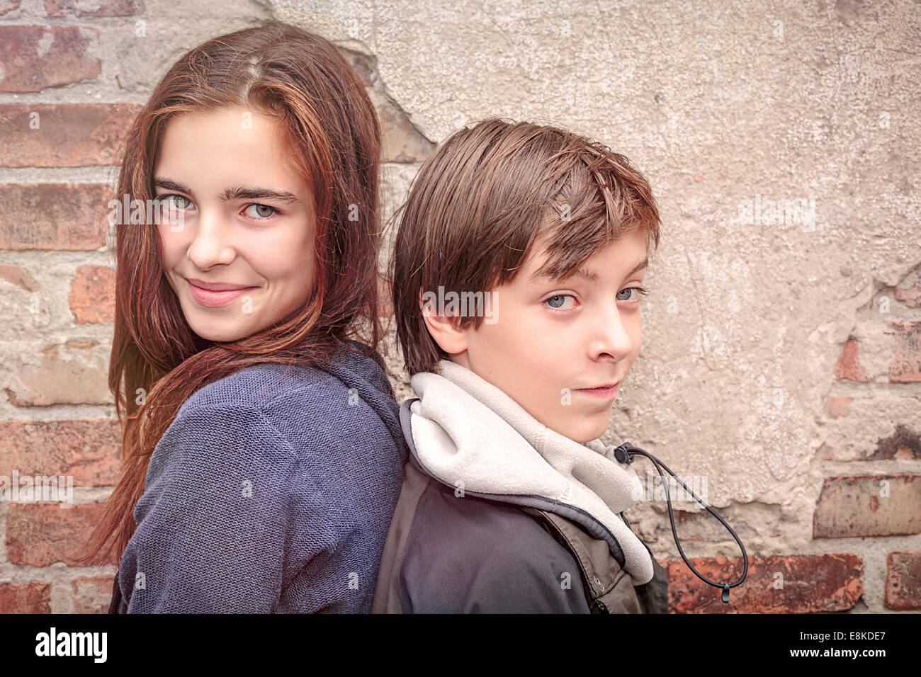 I fratelli di schiena nella parte anteriore di un vecchio muro di mattoni Foto Stock