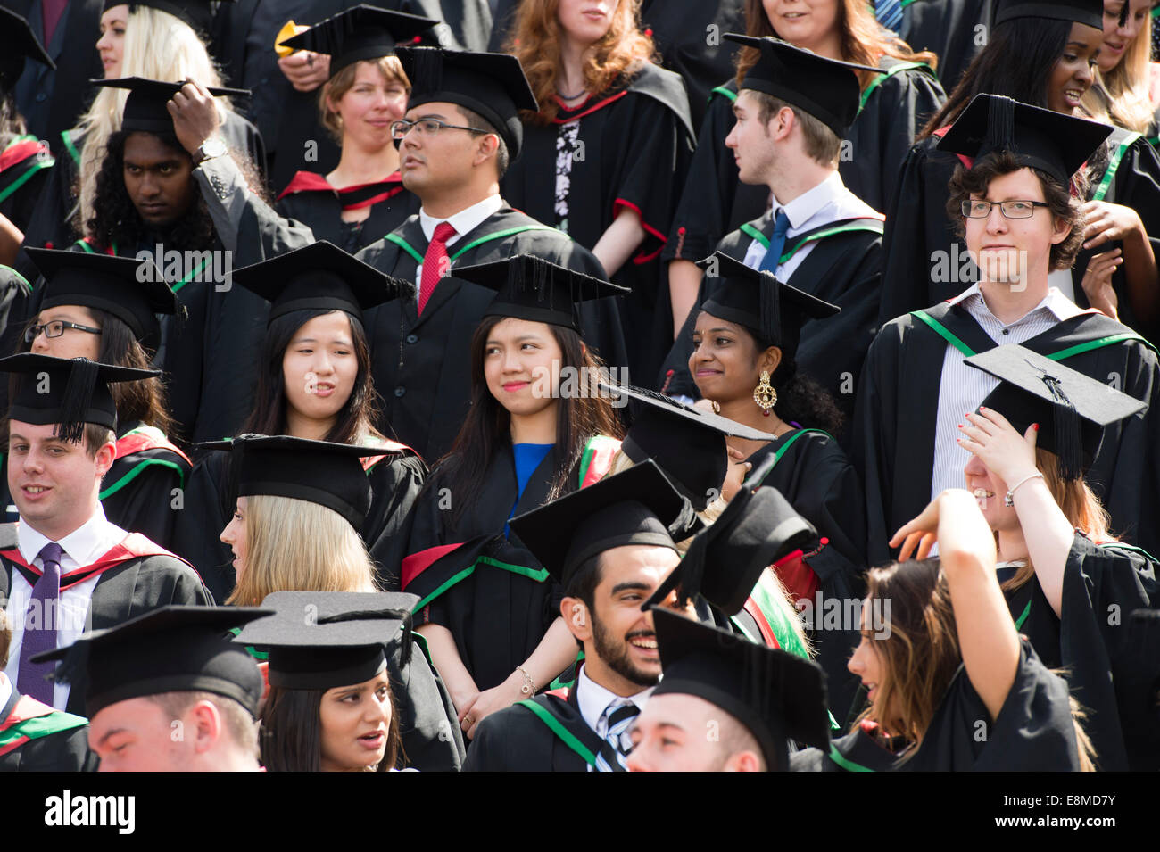 Una folla di etnie miste europee e asiatiche maschio stranieri e collegio femminile gli studenti nelle loro tradizionali abiti e schede di malta dopo la laurea sul giorno di graduazione Aberystwyth University, Wales UK 2014 Foto Stock