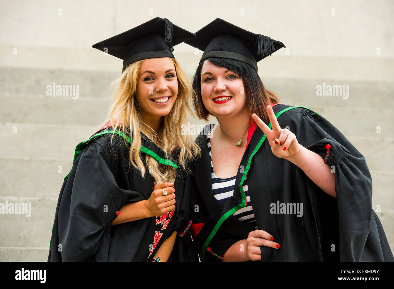 Due felici donne studenti in abiti tradizionali e schede di malta la laurea sul giorno di graduazione Aberystwyth University, Wales UK Foto Stock