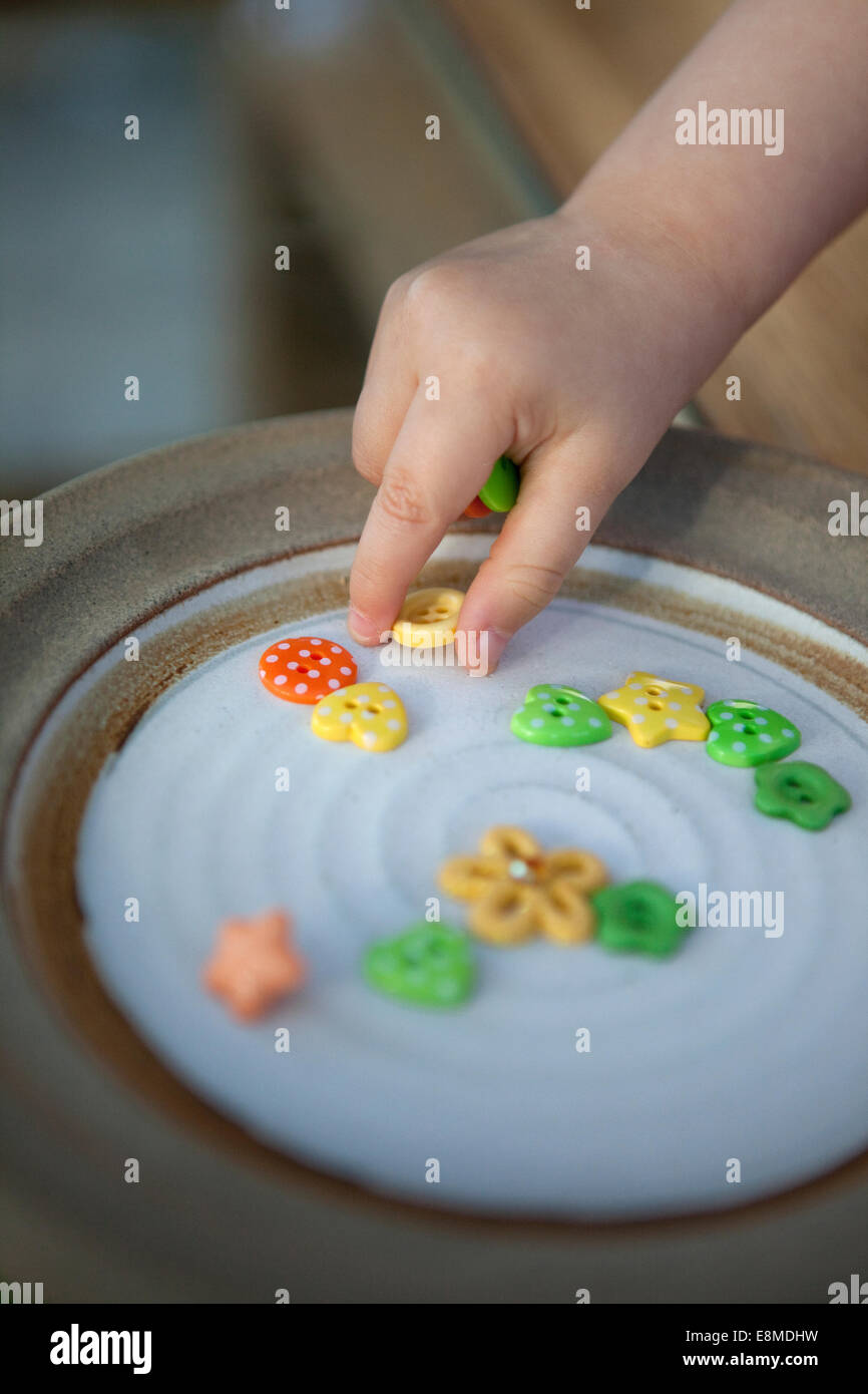 Il Toddler prelievo di piccoli oggetti utilizzando la pinza di presa. Foto Stock