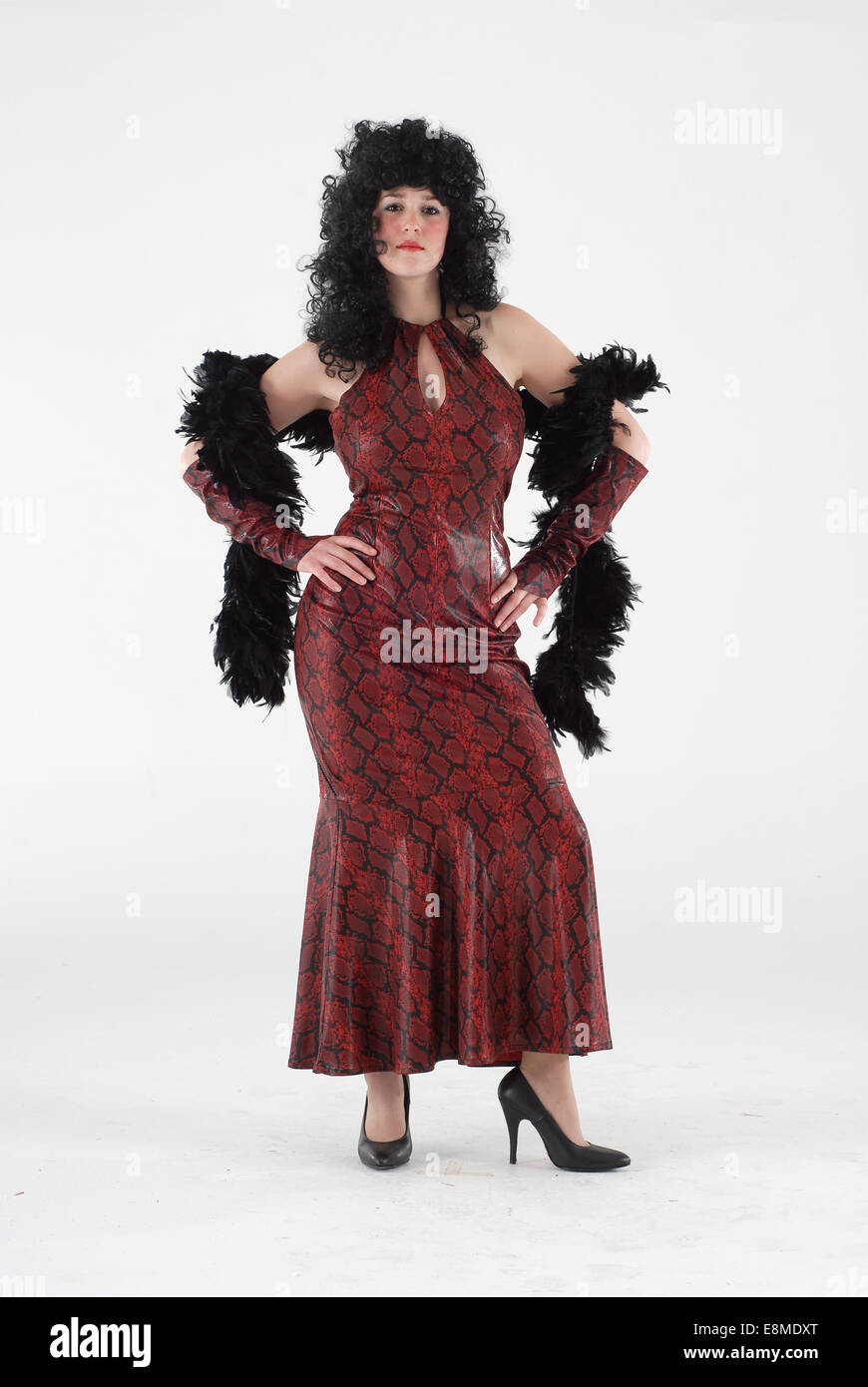 Donna in costume costume di commedia in un rosso pelle di serpente, abito con piume e bower parrucca nero Foto Stock