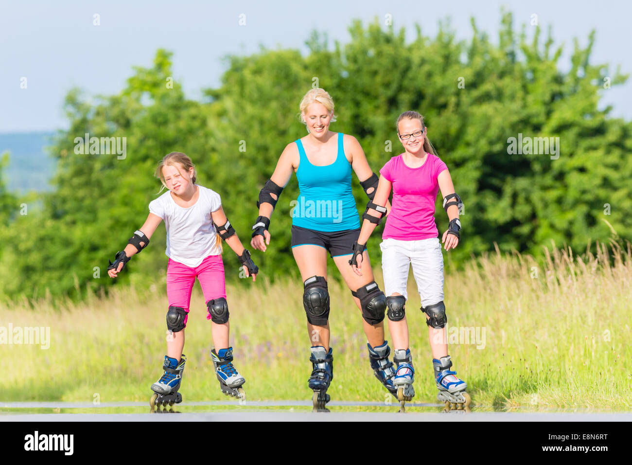 La madre e le figlie con i rollerblade con pattini a rotelle in linea sul vicolo del paese Foto Stock