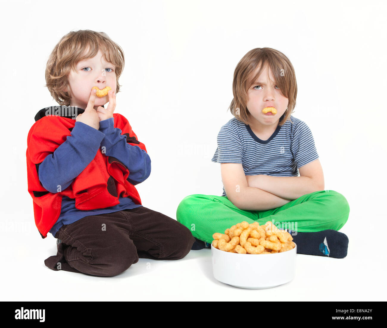Due ragazzi seduti con riccioli di arachidi, sfondo bianco Foto Stock