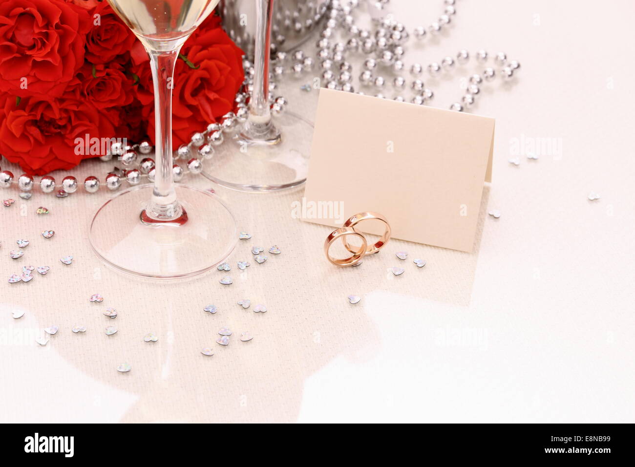 Due golden gli anelli di nozze con carta, champagne e rose rosse Foto Stock