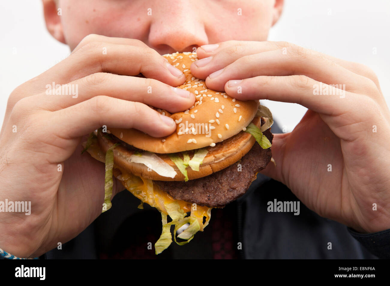 Un adolescente di mangiare un McDonald's Big Mac burger. Foto Stock