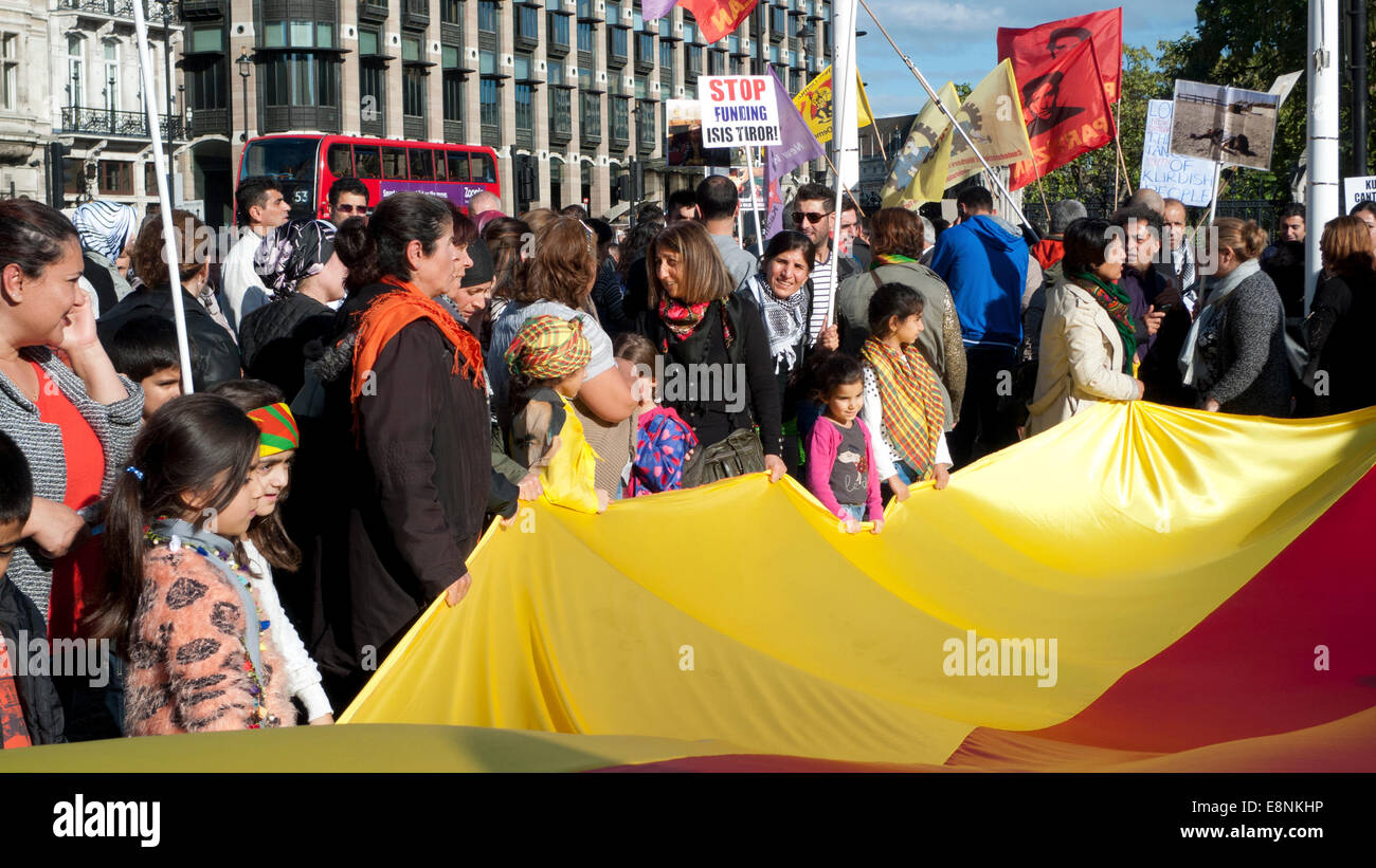 La piazza del Parlamento, Londra UK. 11 ottobre 2014. Il popolo curdo si riuniscono in piazza del Parlamento a manifestare contro lo strapotere di aggressione di Iside, mancanza di sostegno nel proteggere i curdi nella città di Kobane in Siria e wave anti turco governo AKP cartelloni . Le donne e i bambini in possesso di un banner con i colori della bandiera curda per dimostrare la loro solidarietà nella lotta contro uno Stato islamico. Una targhetta invita ad una sosta al finanziamento ISIS terrore. Kathy deWitt/Alamy Live News Foto Stock