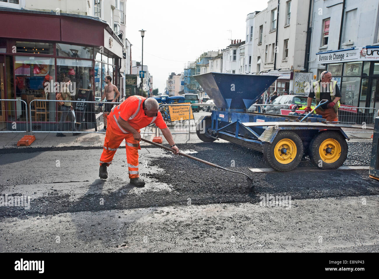 Foto di Roger Bamber : 23 Settembre 2014 : Autostrada Road lavoratore diffondere i trucioli dal Chipper su una spianata la strada principale Foto Stock