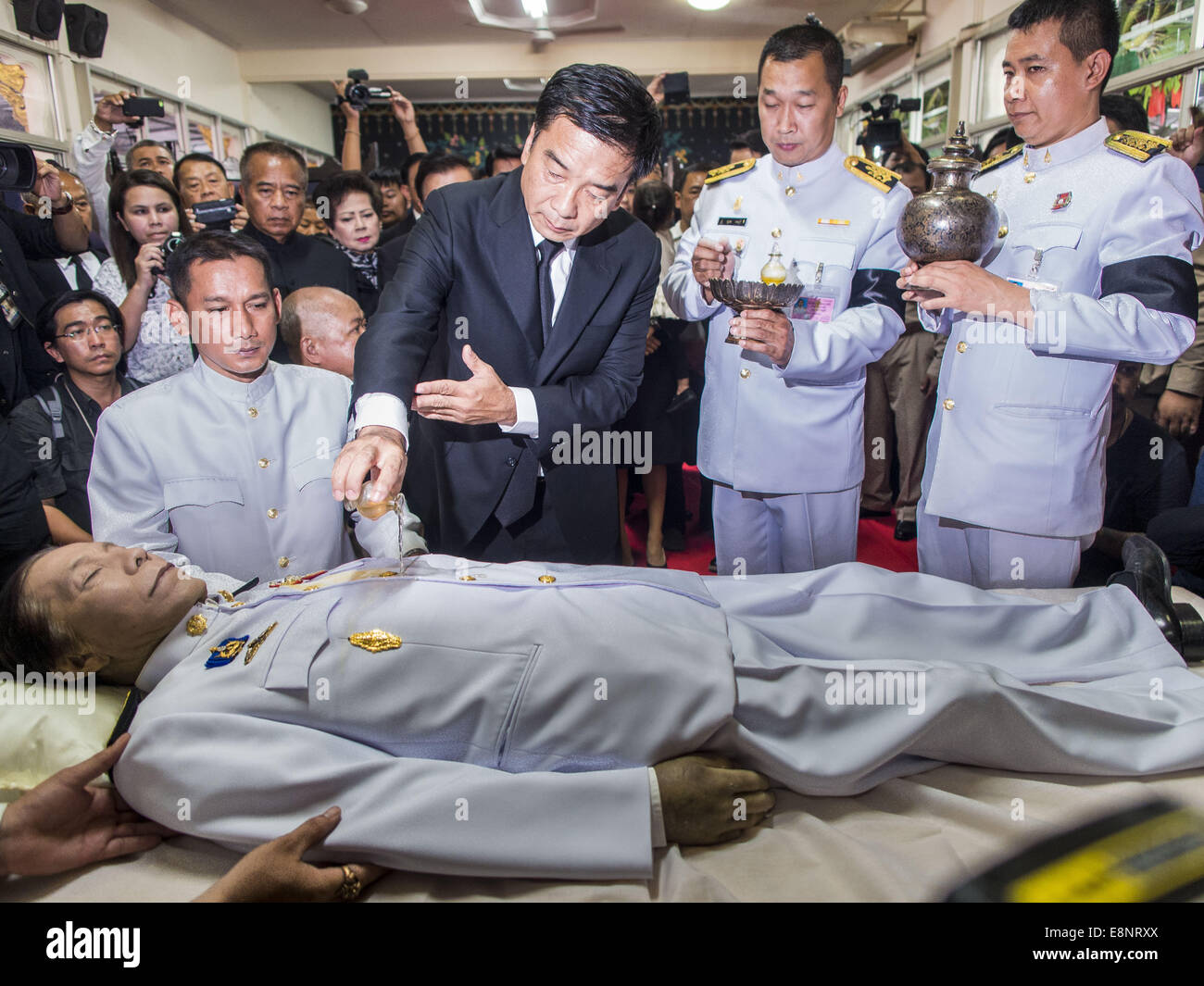 Bang Bua Thong, Nonthaburi, Tailandia. Xii oct, 2014. Gli oli profumati sono versata al di sopra del corpo di Apiwan Wiriyachai durante il primo giorno di riti funebri per Apiwan al Wat Bang Phai in Bang Bua Thong, un sobborgo di Bangkok, domenica. Apiwan era un prominente Maglietta rossa leader, membro della Pheu Thai Party dell ex primo ministro Yingluck Shinawatra, e da un membro del parlamento thailandese. Il governo militare che depose il governo eletto nel maggio 2014, caricato con Apiwan di lesa maestà per aver insultato la monarchia tailandese. Piuttosto che affrontare le cariche, Apiwan fuggiti in Thailandia per le Filippine. Foto Stock