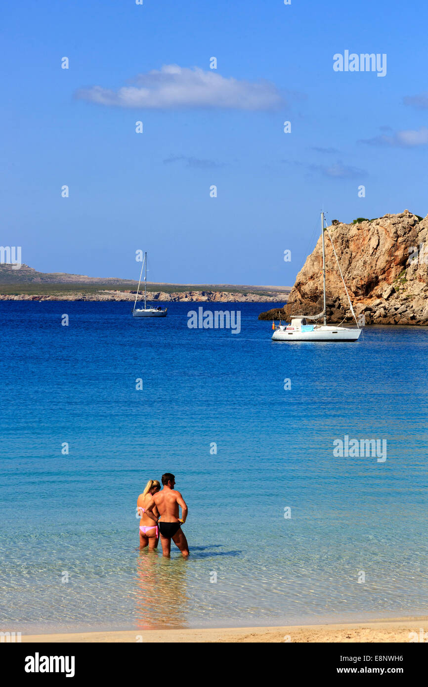 L uomo e la donna in piedi nei fondali del mare Mediterraneo a Arenal d'en Castell, Menorca, Spagna Foto Stock