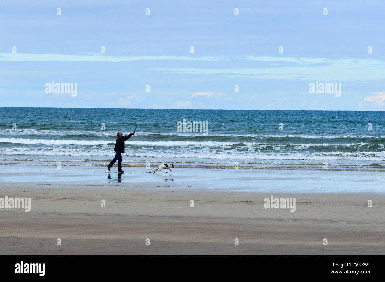 Contea di Londonderry, Irlanda del Nord, Regno Unito. Xii Ottobre 2014. Un uomo che cammina il suo cane sulla spiaggia in discesa, nella contea di Londonderry oggi nel tardo pomeriggio come il clima autunnale continua. Credito: George Sweeney/Alamy Live News. Foto Stock