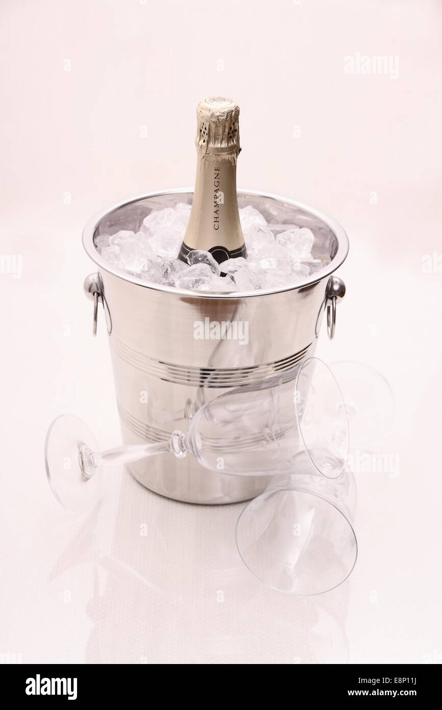 Bottiglia di Champagne nel refrigeratore e due bicchieri di champagne su sfondo lucido Foto Stock