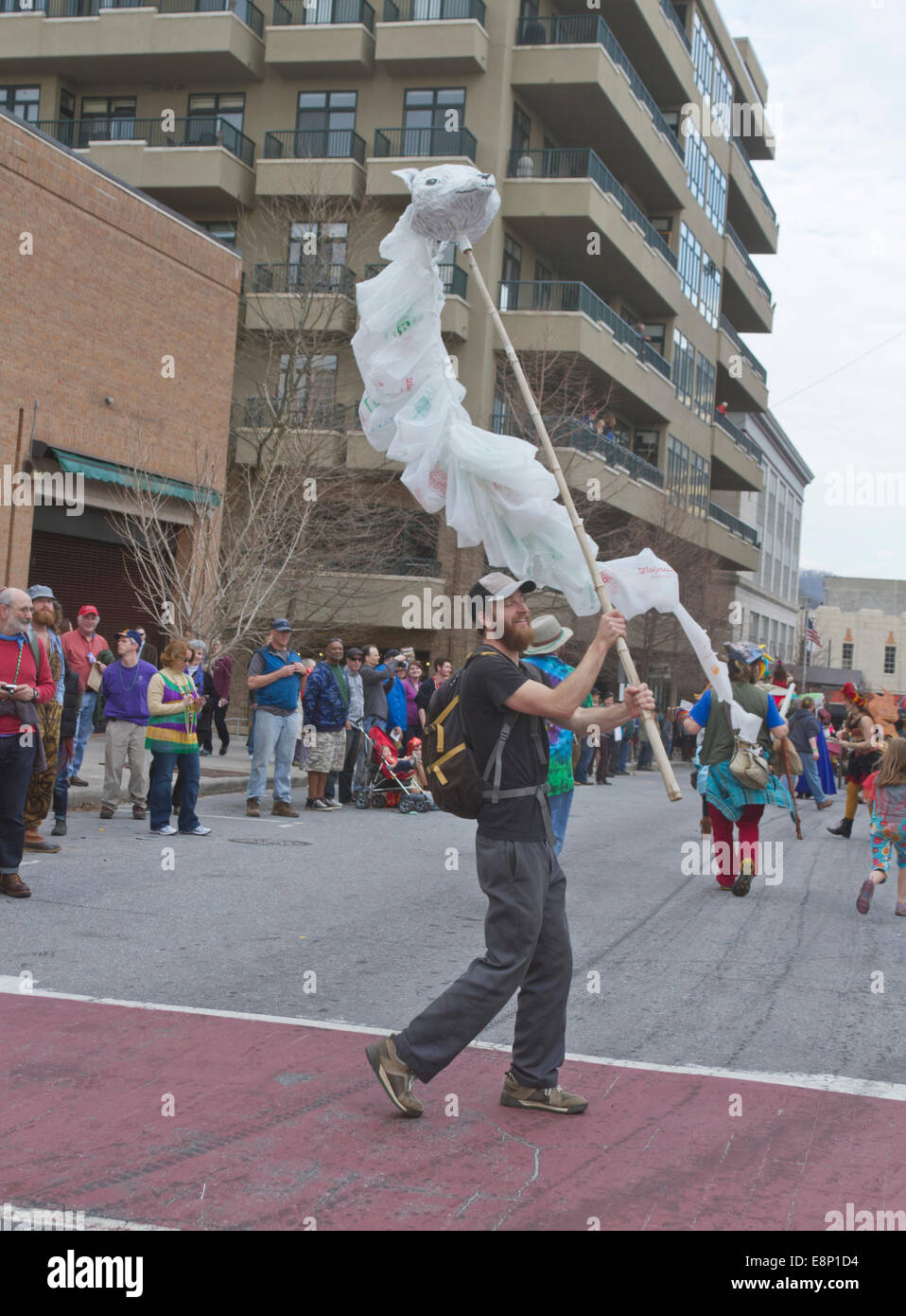 Un uomo in marcia in un Mardi Gras Parade onde un artistico, fluente testa di lupo marionetta creati al di fuori di sacchetti di plastica usa e getta Foto Stock