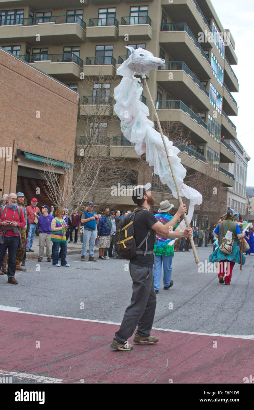 Un uomo in marcia in un Mardi Gras Parade onde un artistico, fluente testa di lupo marionetta creati al di fuori di sacchetti di plastica usa e getta Foto Stock