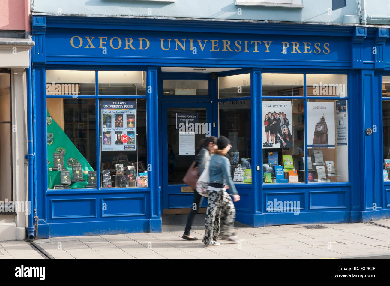 Due persone (motion sfocata) passando la Oxford University Press Bookshop in High Street, Oxford. Foto Stock