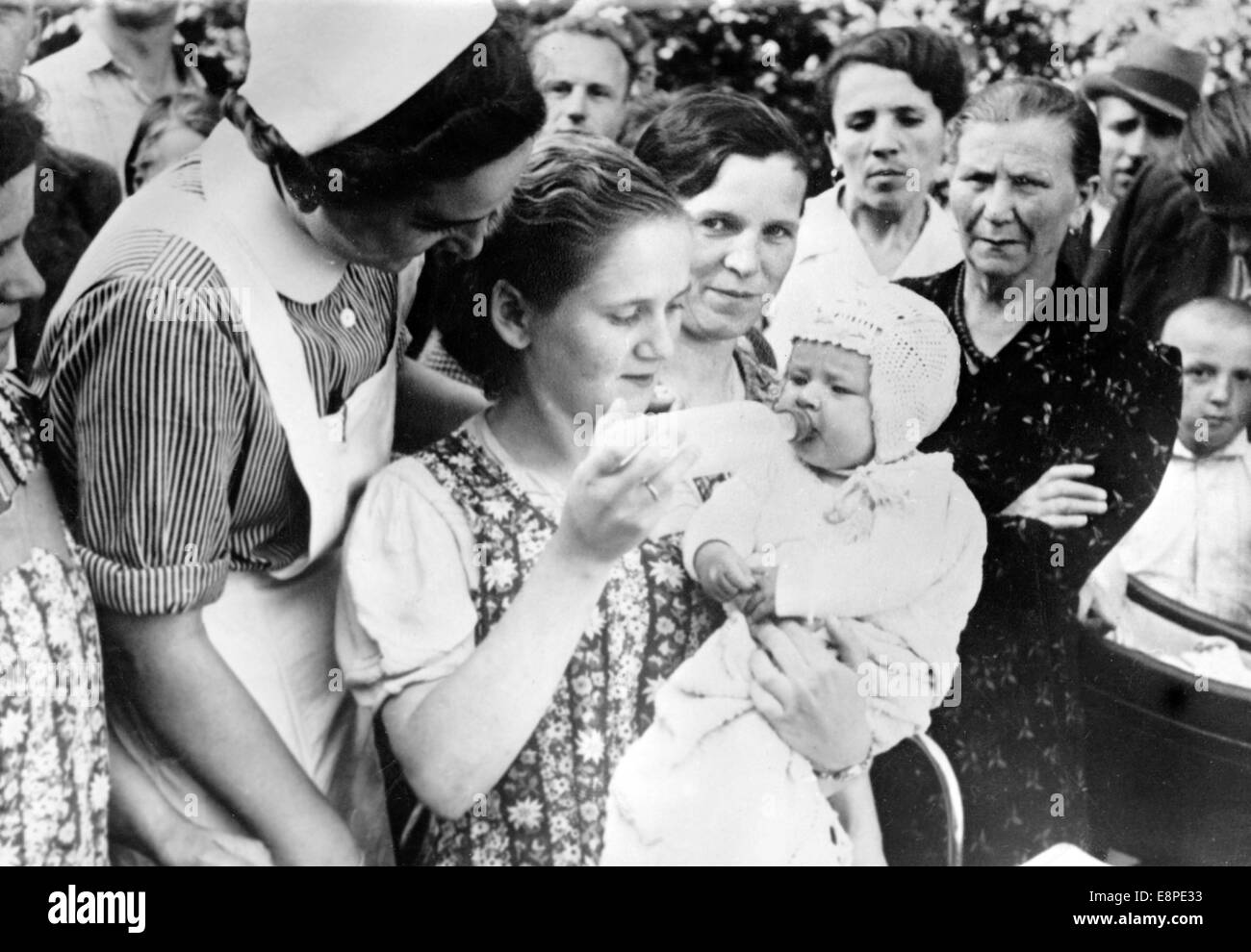 Il quadro della propaganda nazista mostra i rifugiati tedeschi dalla Polonia nella zona di Waldenburg (oggi Walbrzych, Polonia), agosto 1939. Il testo originale sul retro dell'immagine recita: 'Fuggire dal terrore spietato. In un campo profughi nella zona di Waldenburg: Molte forze di assistenza sono pronte ad aiutare i rifugiati. Il piccolo bambino, che viene nutrito di latte, non sa ancora che suo padre sta languendo in una prigione polacca." Fotoarchiv für Zeitgeschichtee - NESSUN SERVIZIO DI CABLAGGIO Foto Stock