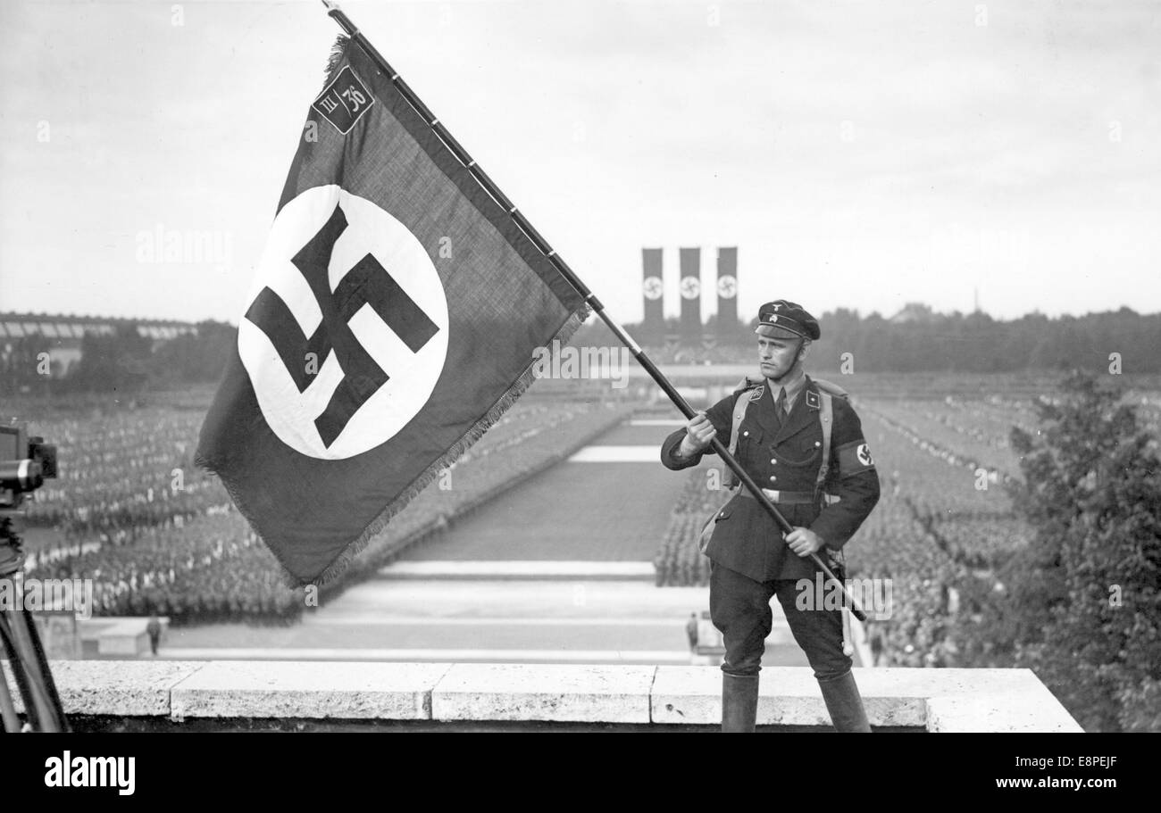 Norimberga Rally 1933 a Norimberga, Germania - Un membro della SS (Schutzstaffel) tiene una bandiera per la telecamera durante la commemorazione dei morti nei raduni del partito nazista. (Difetti di qualità dovuti alla copia storica dell'immagine) Fotoarchiv für Zeitgeschichtee - NESSUN SERVIZIO DI CABLAGGIO – Foto Stock