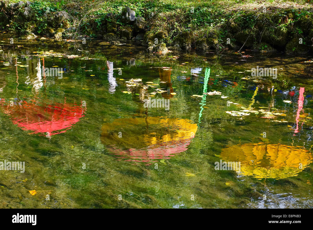 Ombrelloni colorati sono riflesse in un stagno Foto Stock