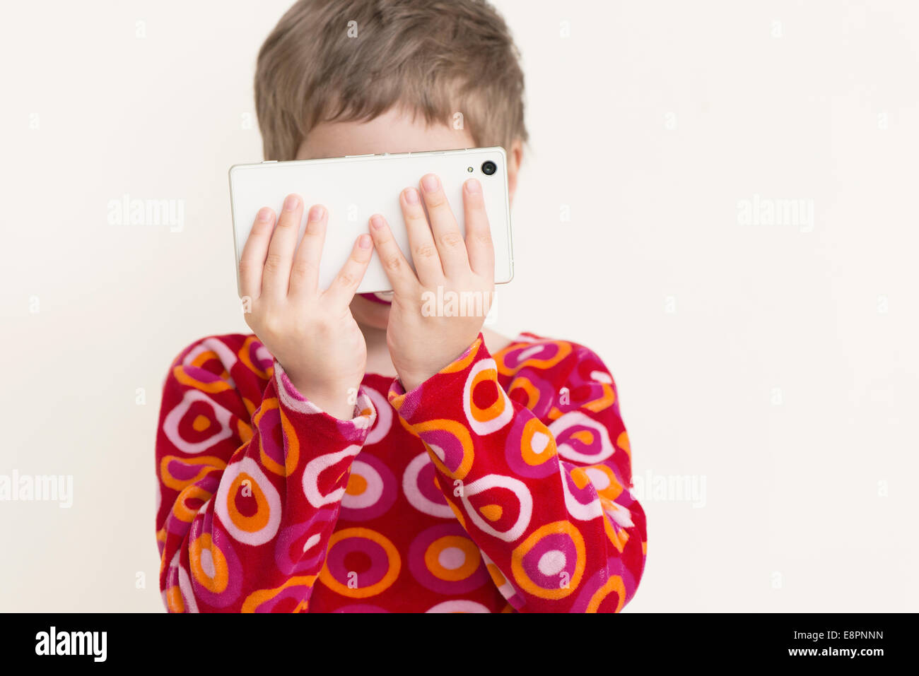 Bambina con abito rosso guardando smart phone. Foto Stock