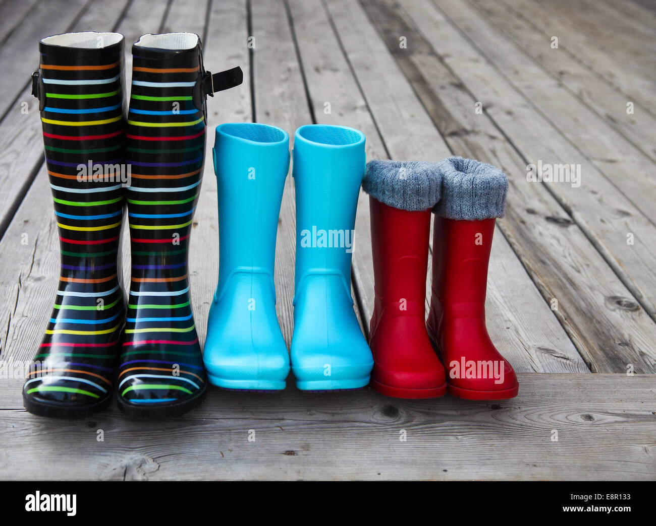 Tre coppie di un colorato stivali da pioggia. Concetto di famiglia Foto Stock