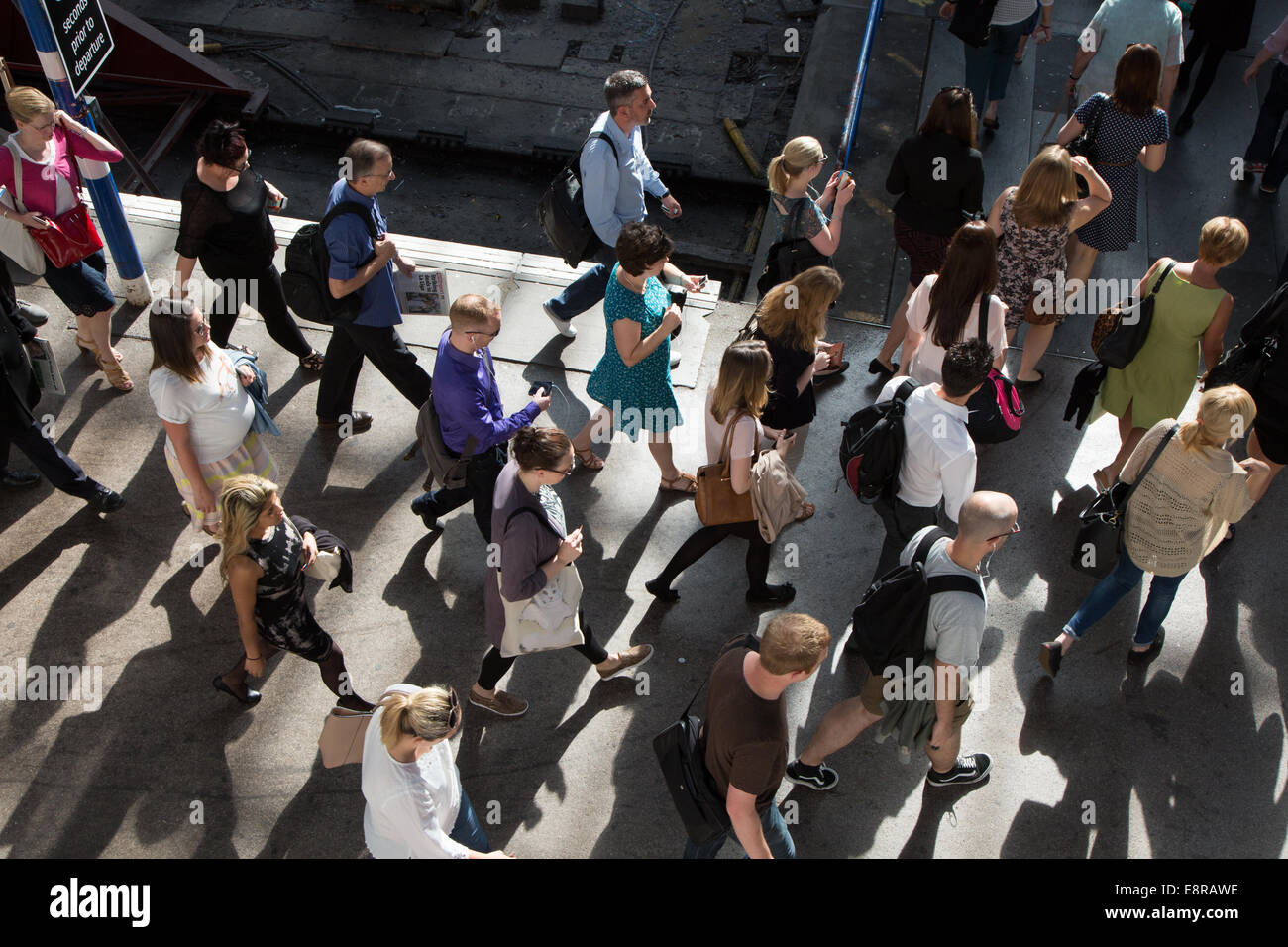 I passeggeri di scendere dal treno e a piedi verso i cancelli del biglietto presso la stazione del treno durante una trafficata mattina d'estate. Foto Stock