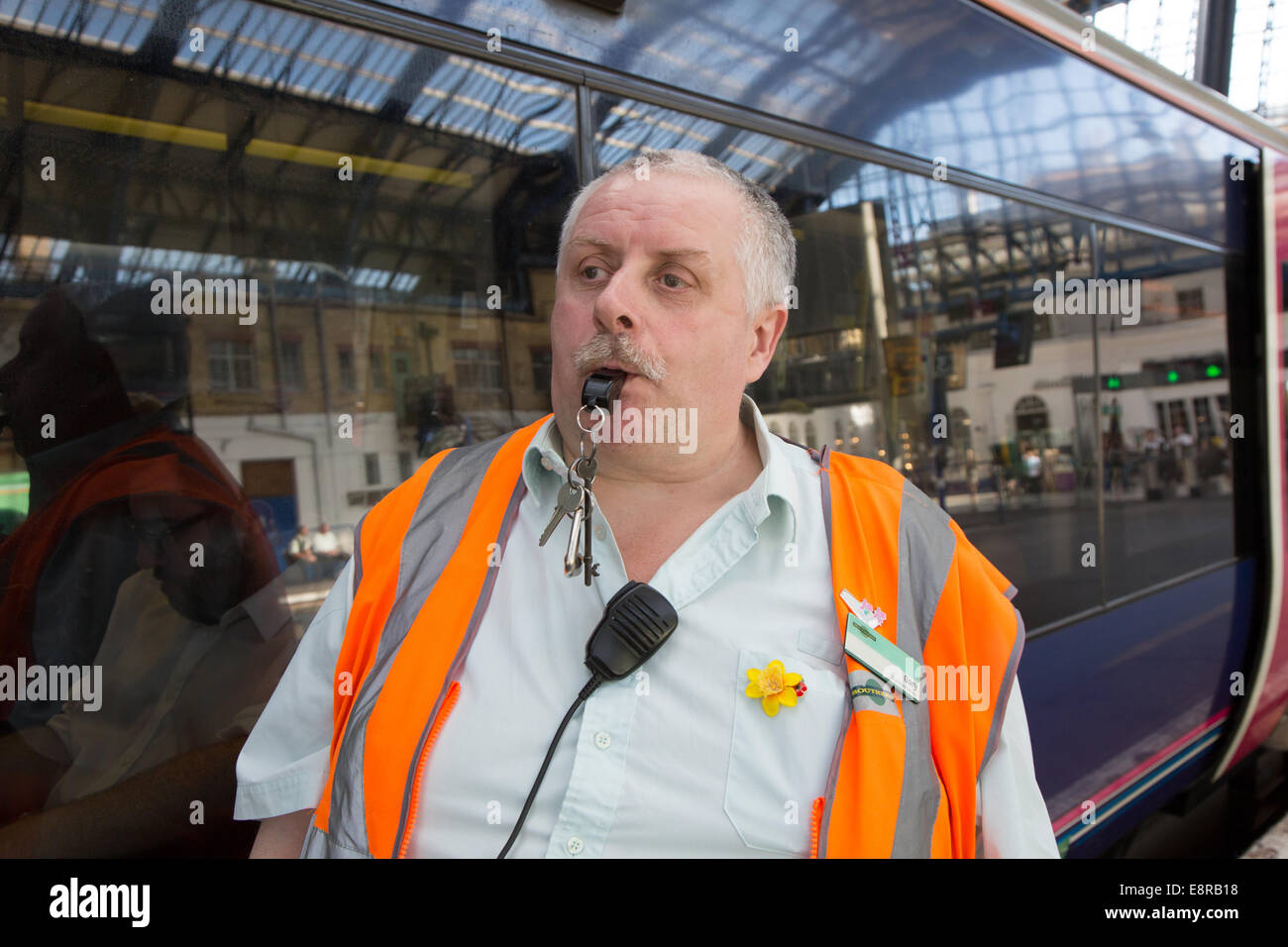 Un uomo di segnale ad una stazione ferroviaria si prepara a soffiare il suo fischio allo scopo di avvisare il conducente di tirare lontano. Brighton Foto Stock