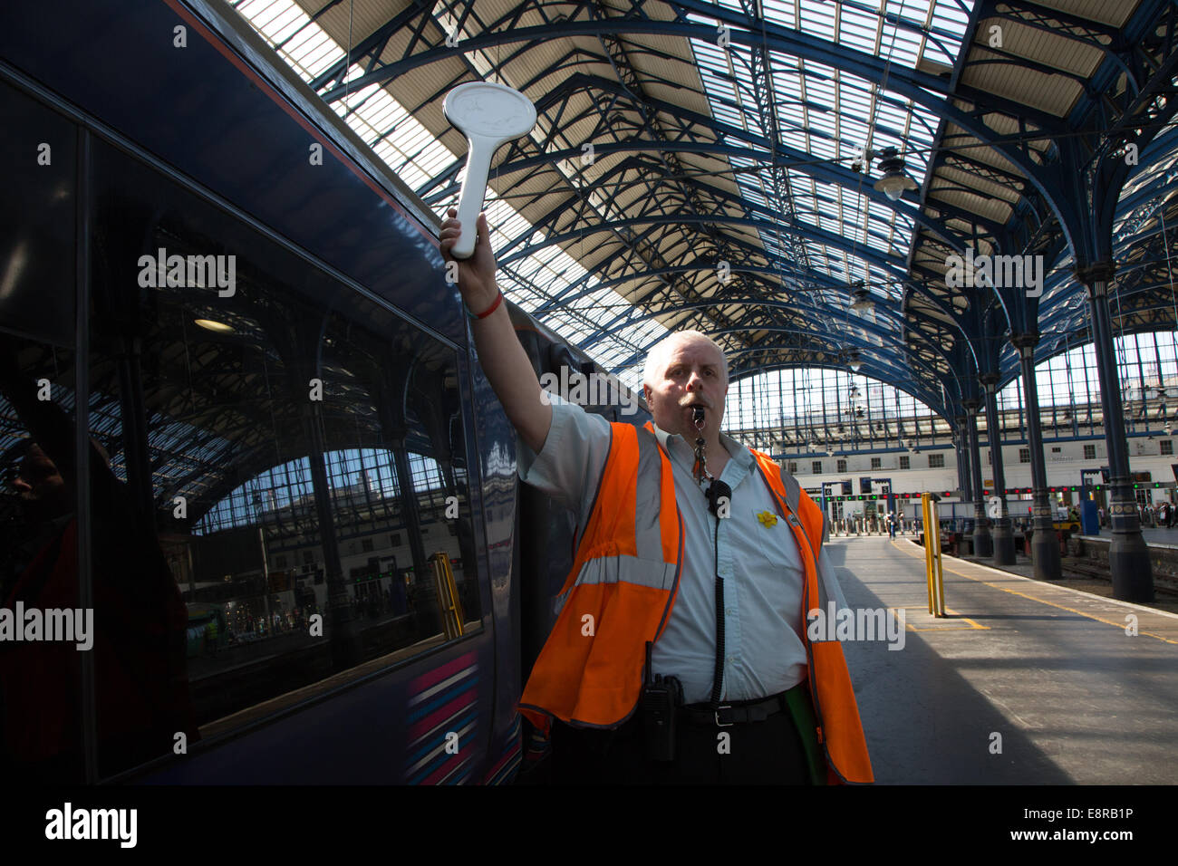 Un segnale di uomo alla stazione ferroviaria di Brighton si prepara a soffiare il suo fischio allo scopo di avvisare il conducente di tirare lontano. Foto Stock
