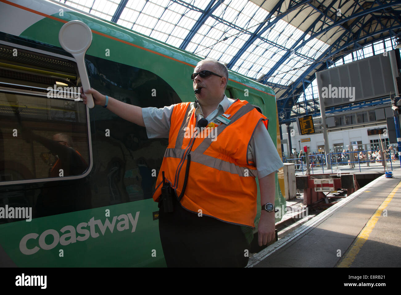 Un segnale di uomo presso la stazione di Brighton si prepara a soffiare il suo fischio allo scopo di avvisare il conducente di tirare lontano. Foto Stock