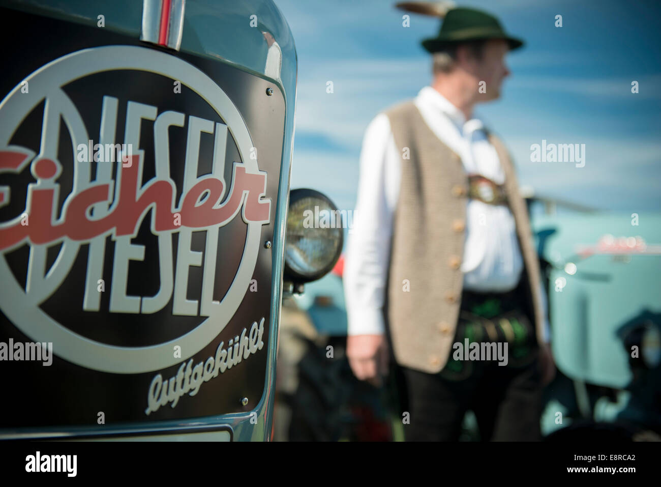 L'uomo con i tradizionali abiti bavarese Eicher dietro il trattore Foto Stock