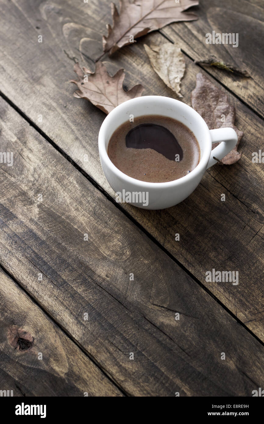 Tazza di caffè in autunno cadono le foglie e superficie in legno sfondo Foto Stock