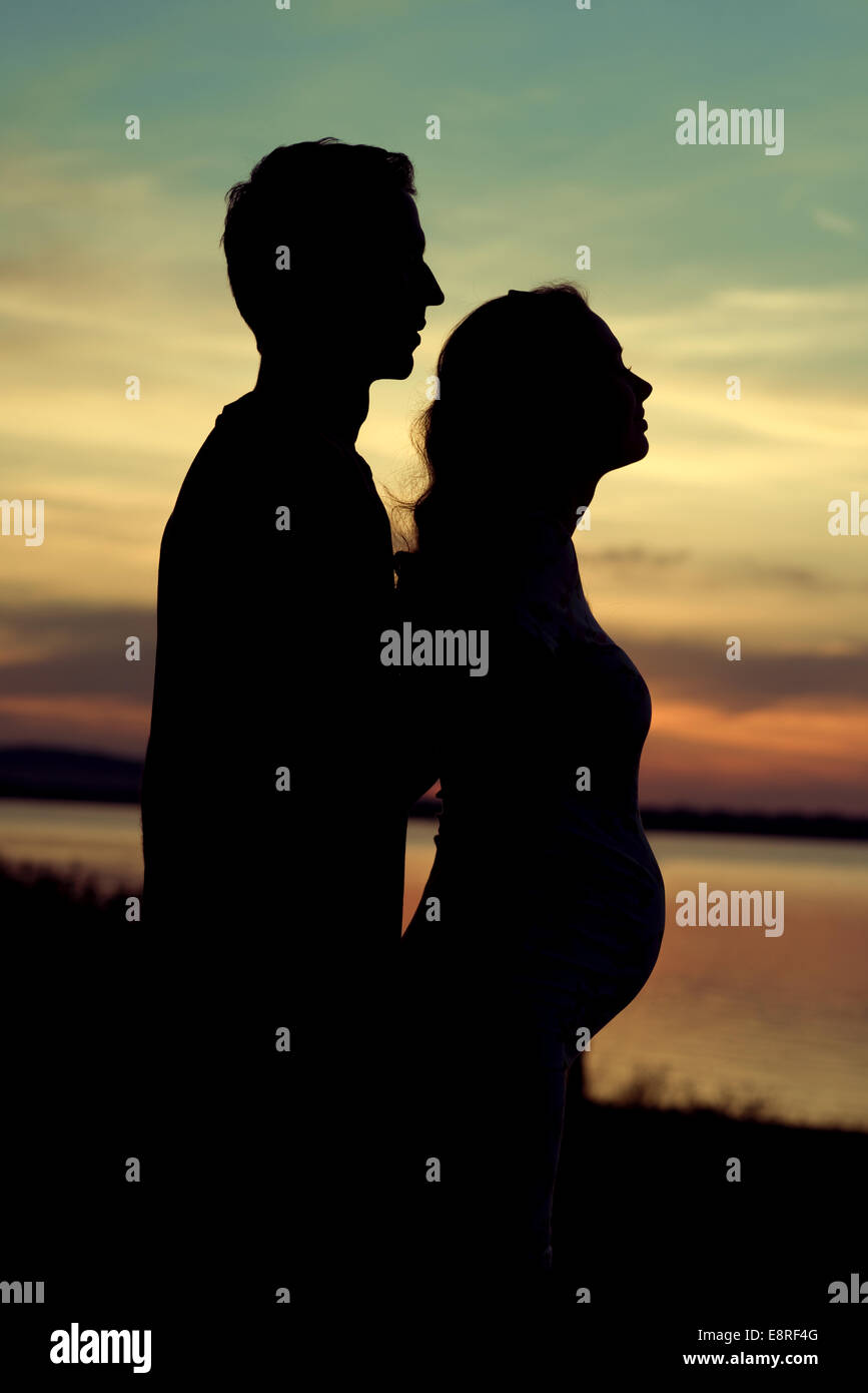 Silhouette dell'uomo abbracciando la sua gravidanza ragazza Foto Stock