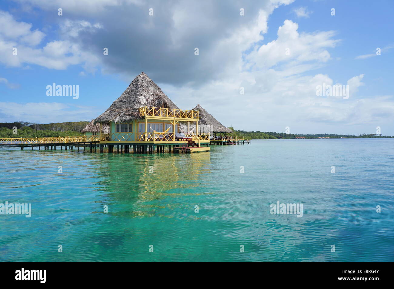 Resort caraibico con bungalow con tetto in paglia su acqua, Bocas del Toro, America centrale e di Panama Foto Stock