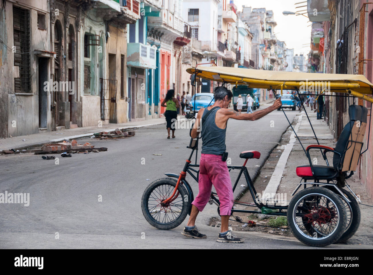 Havana Cuba - un uomo di parcheggiare la sua bicicletta turistica cabina tra edificio fatiscente detriti nel centro di Avana street. Foto Stock