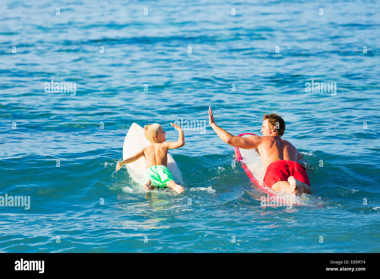 Felice padre e figlio giovane andando surfare insieme. Dando a ogni altro un Hi-Five! Foto Stock