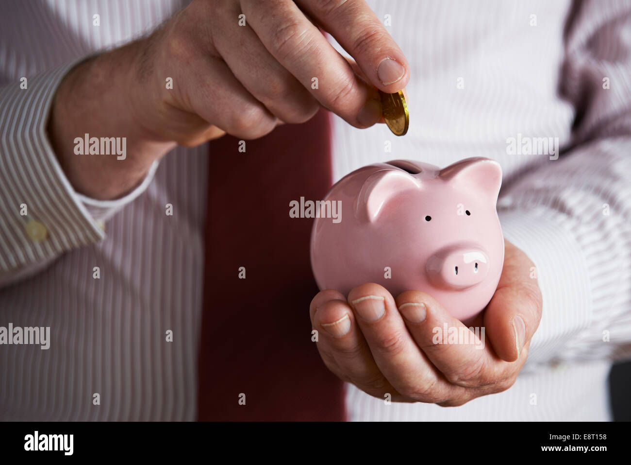 Imprenditore mettendo moneta nel salvadanaio Foto Stock